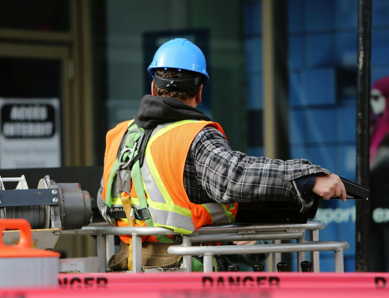 WDS crew member on a lift, safety harness on, job site behind